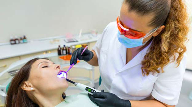 Adult female dentist treating patient woman teeth. Medicine, den