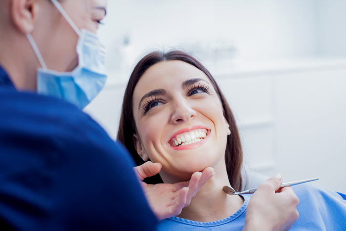 smiling women patient on chair while taking treatment with dentist